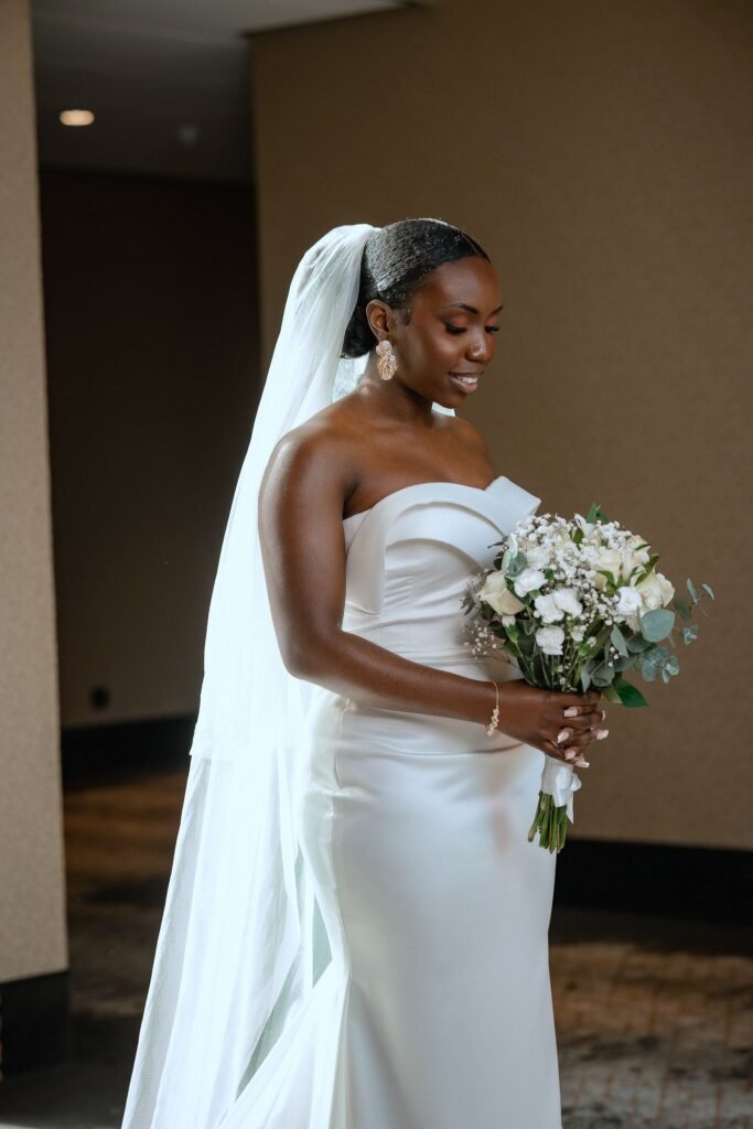 Bride in a clean strapless crepe gown holding a white bouquet