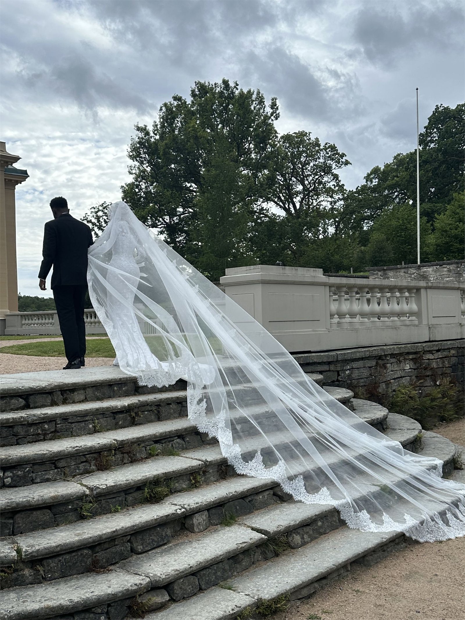 A cathedral-length veil lifted by the wind as it trails down a flight of stone steps