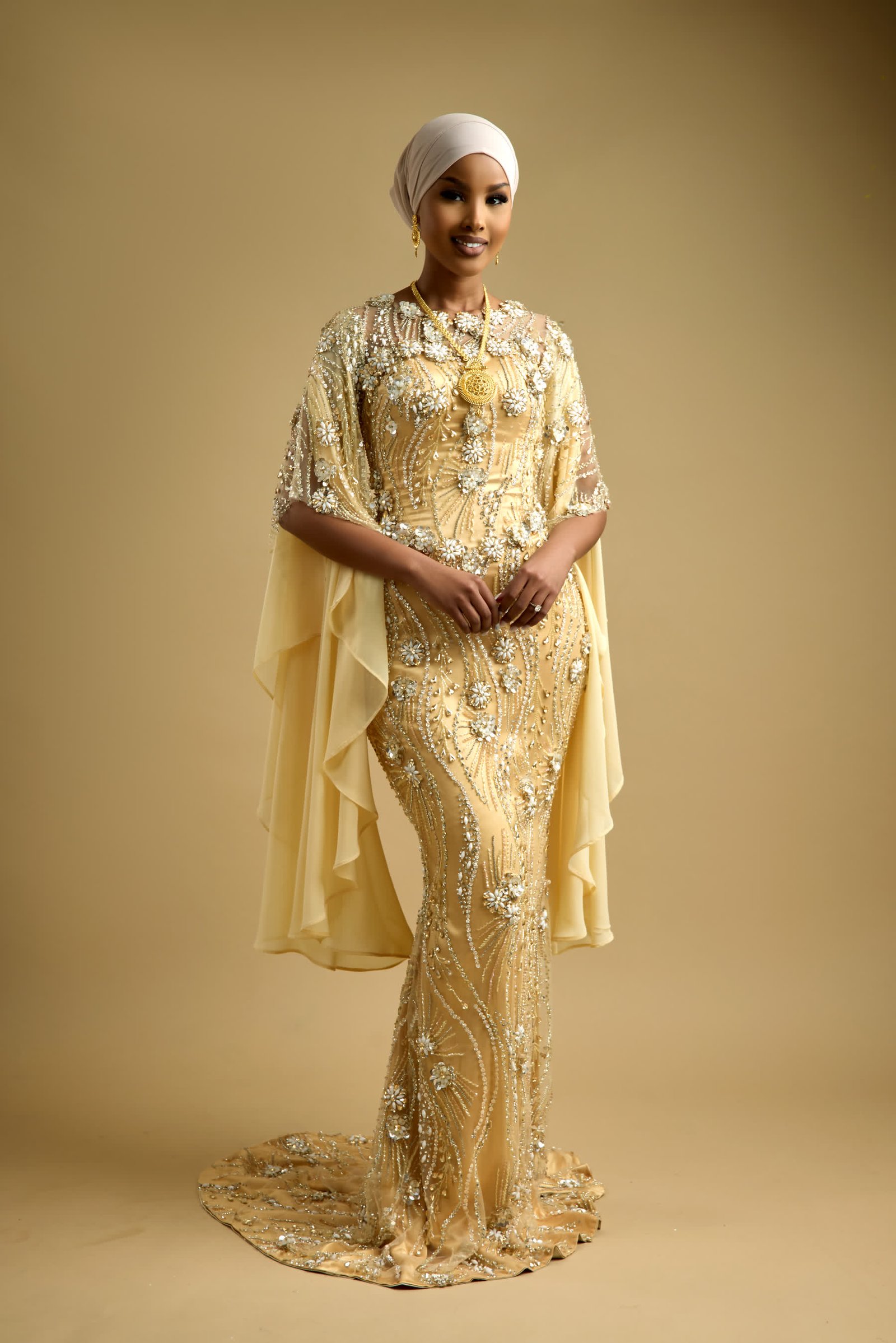Ivory wrapped head covering styled to sit with the neckline of a beaded cape gown