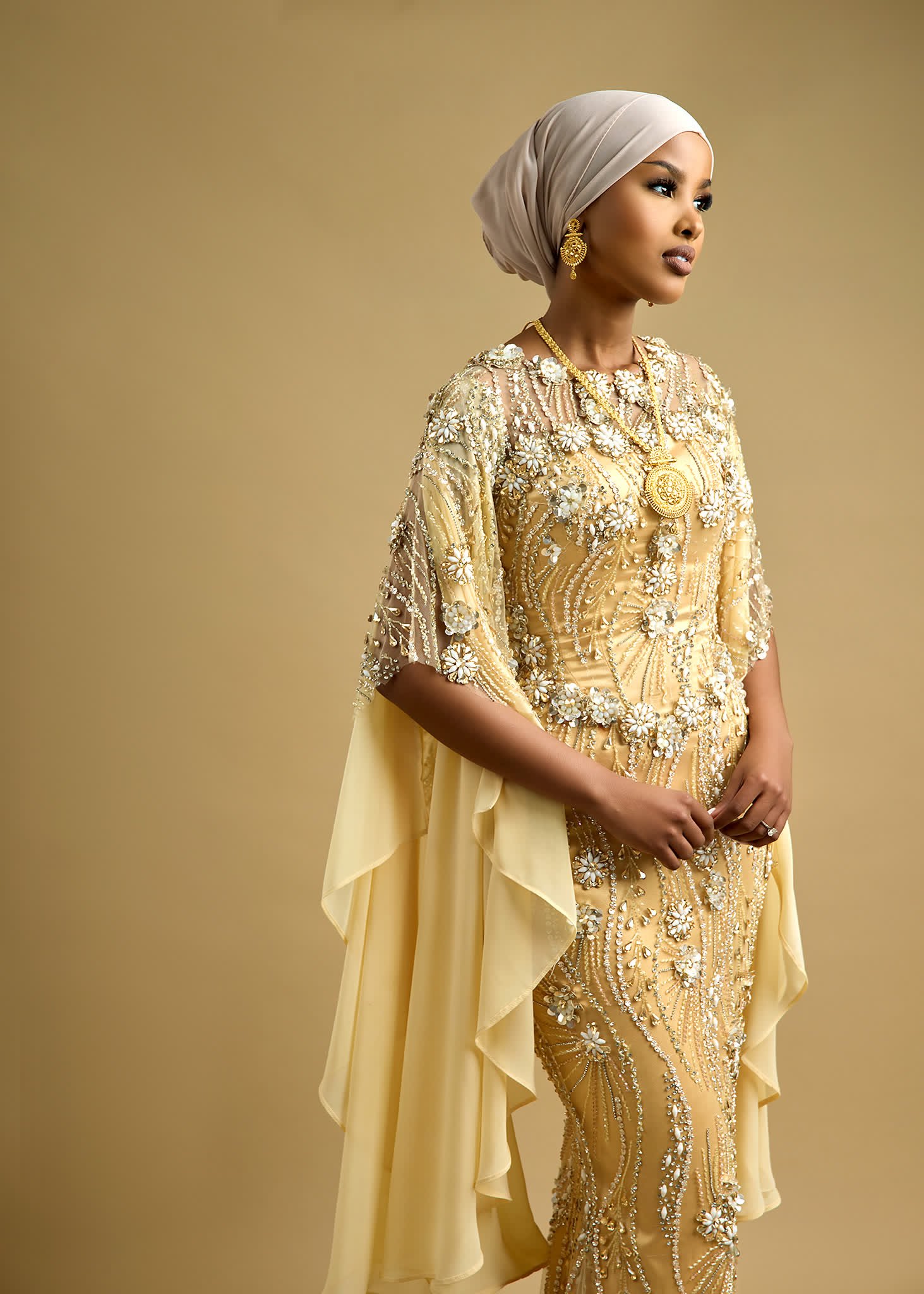 Beaded gown with draped chiffon cape sleeves falling from a covered shoulder